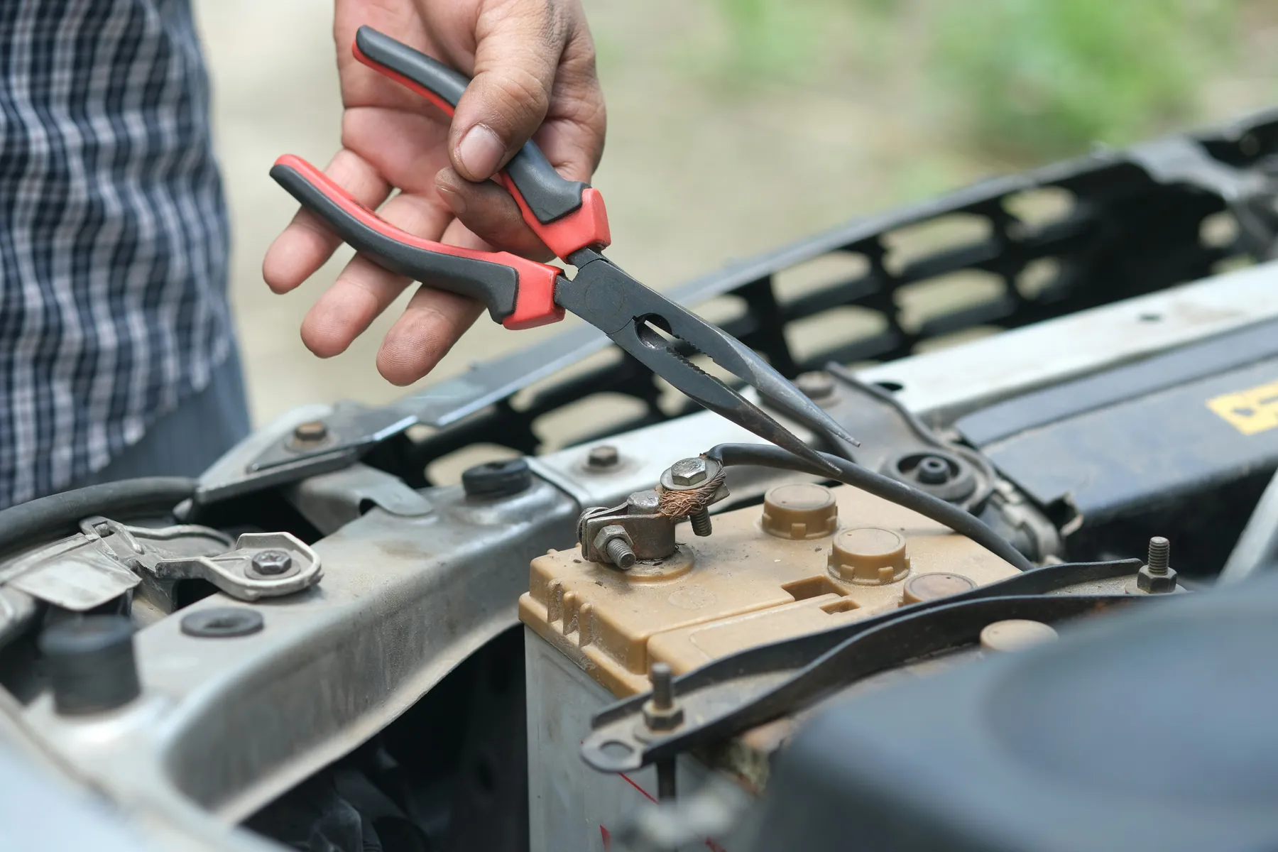 Technician checking a car battery terminal