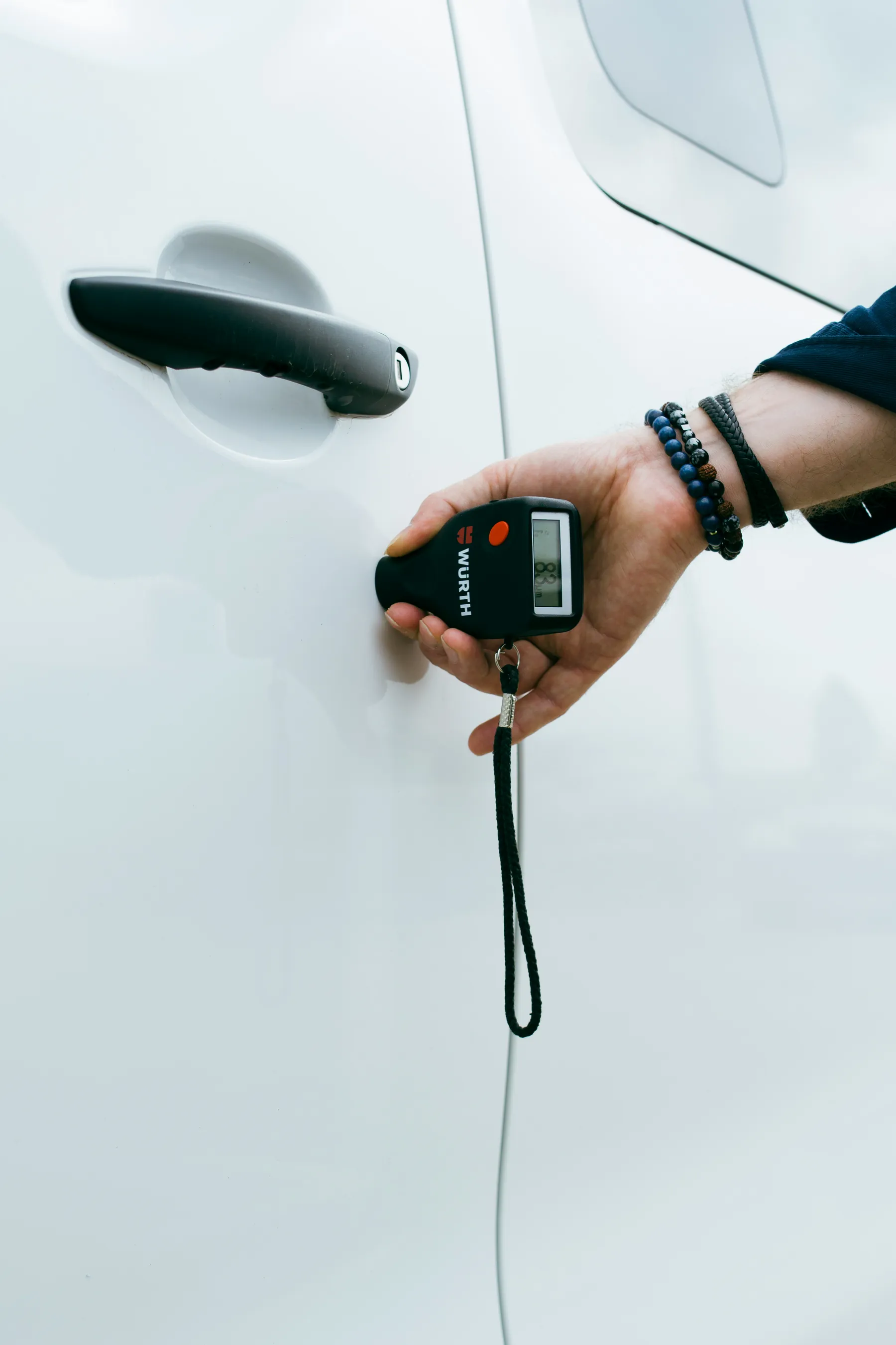 Paint thickness gauge checking a white car panel